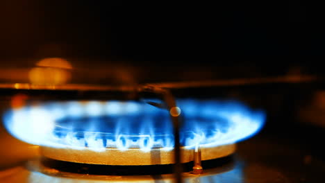 close up of a gas burner igniting with blue flames on a stove