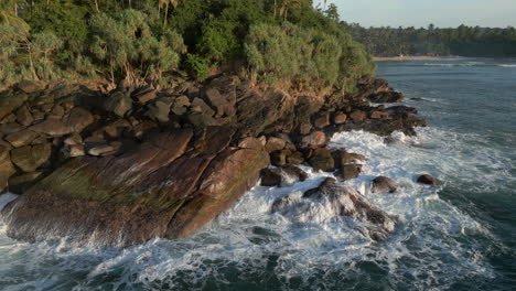 Low-Aerial-Drone-Shot-of-Waves-Crashing-into-Rocky-Shoreline-in-Tropical-Sri-Lankan-Southern-Coast