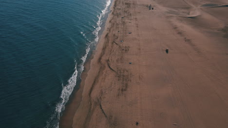 Aerial-view-along-the-shore-of-Maspalomas-beach-and-revealing-the-Maspalomas-lighthouse