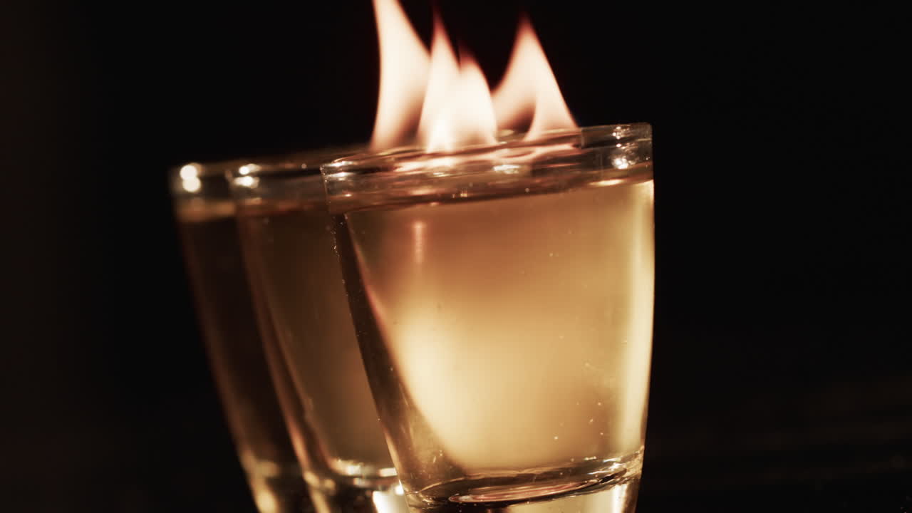 video de alcohol encendido en vasos con llamas de fuego amarillas y espacio de copia sobre fondo negro