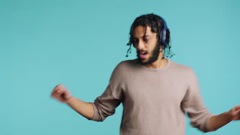 persona eufórica con auriculares, haciendo movimientos de baile, fondo de estudio