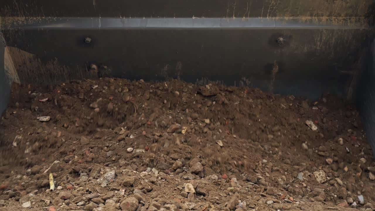 enorme macchina escavatore che fa cadere un grande mucchio di sabbia con pietre sul terreno
