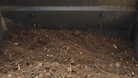 huge excavator machine dropping a big pile of sand with stones on the ground