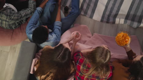 young friends drink beer and eat chips watching tv series