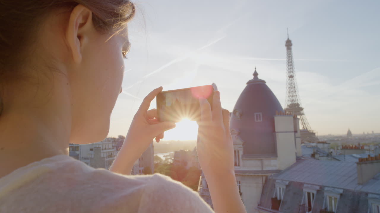 donna felice che usa lo smartphone che scatta foto che si gode di condividere l'esperienza delle vacanze estive a parigi che fotografa la bellissima vista del tramonto della torre eiffel sul balcone da vicino