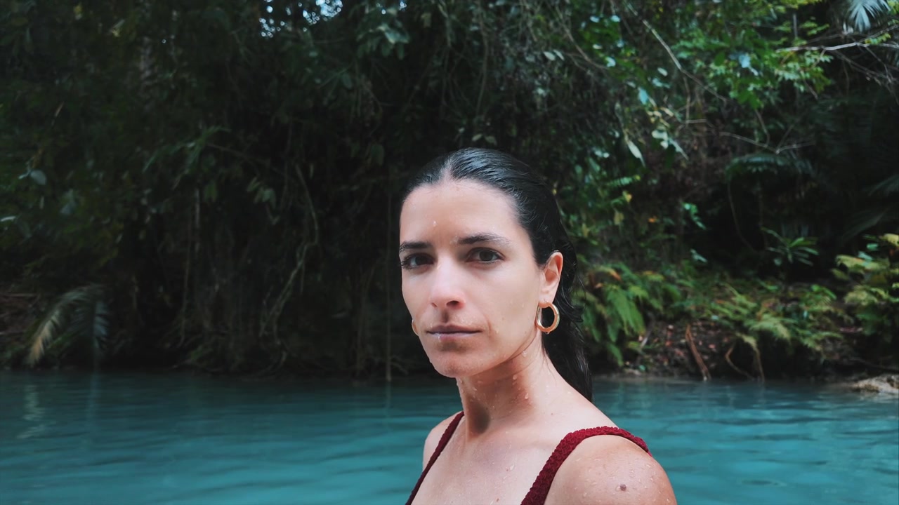 Primo piano di una donna in acqua turchese vicino ad alberi della giungla