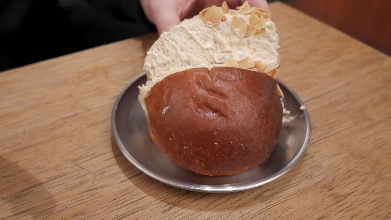 A maritozzo being prepared with cream on a wooden table for a snack