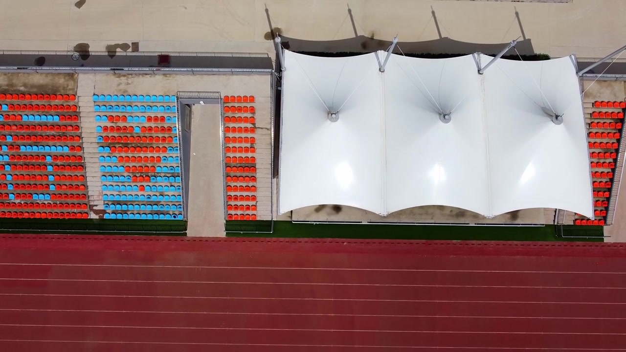 Lodret luftfoto med drone af løbebanen og tribunerne på Beijing Jiaotong Universitets stadion, Weihai Campus, Kina.