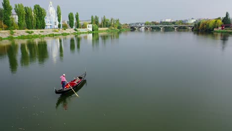 gondola floating along the river. woman enjoying time in a boat on the city background in the evening. aerial view. camera moves round.