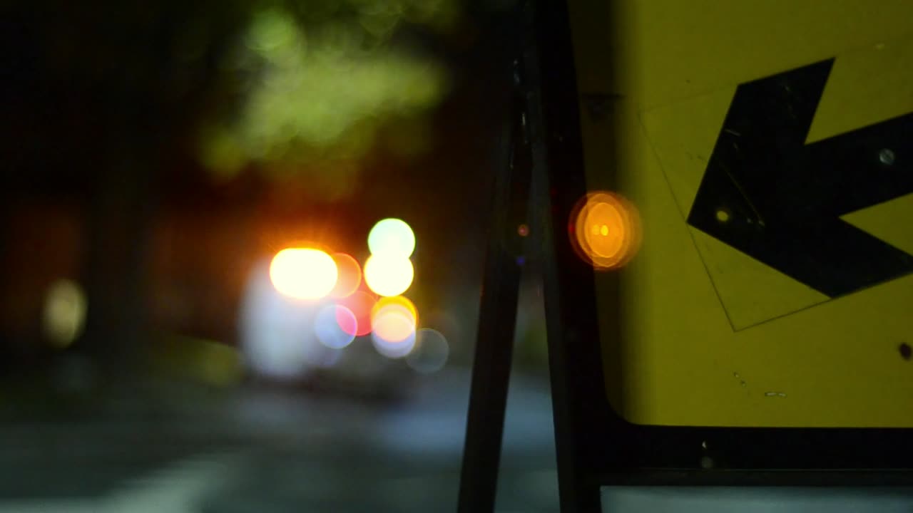 señal de tráfico de la noche que señala la dirección con el tráfico bokeh