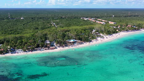 aerial-of-mexican-jungle-coastline-at-Playa-Xpu-Ha-Beach-on-sunny-summer-day-with-tourists-swimming-in-beautiful-turquoise-blue-water