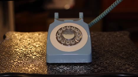 un viejo teléfono en un fondo de mesa de metal con un hombre recogiendo el teléfono y colgándolo.