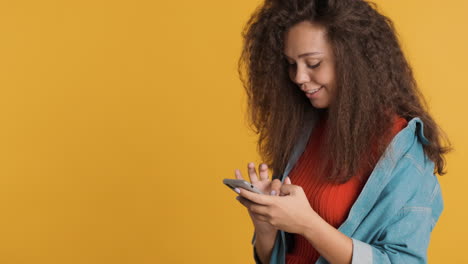 una mujer caucásica de cabello rizado enviando mensajes de texto en su teléfono inteligente.