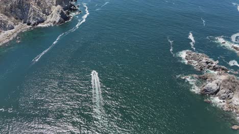 Video-drone-capturing-boat-navigating-waters-of-Bahía-Cacaluta-in-Huatulco,-Oaxacan-coastline-in-Mexico