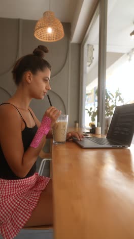 mujer trabajando en una computadora portátil en un café