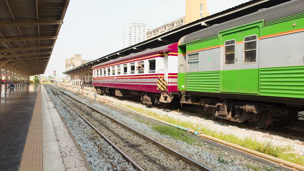 Un treno passeggeri parte da una piattaforma ferroviaria soleggiata alla stazione di Hua Lamphong a Bangkok