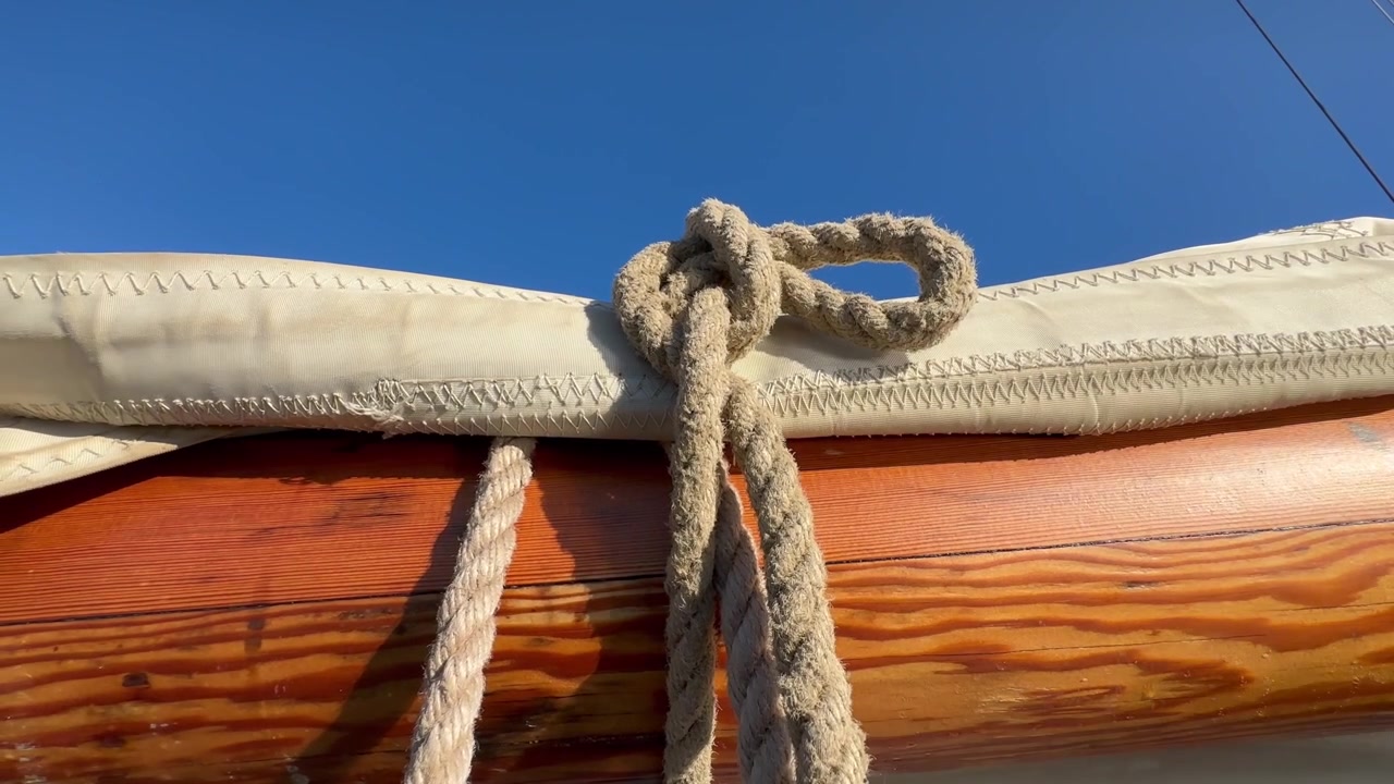 Closeup of sailing ship boom with sail and rope.