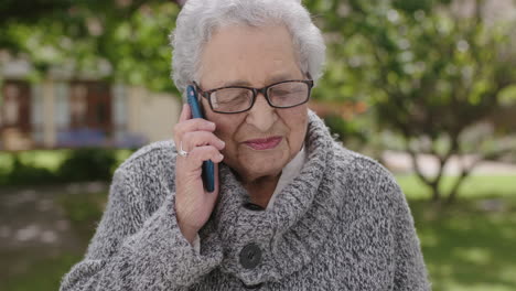 portrait of elderly mixed race woman talking on phone enjoying chatting in sunny garden