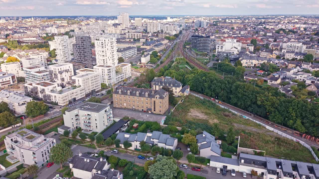 Drone advancing above La Courrouze district showing tracks, housing blocks and cityscape, in Rennes - Brittany