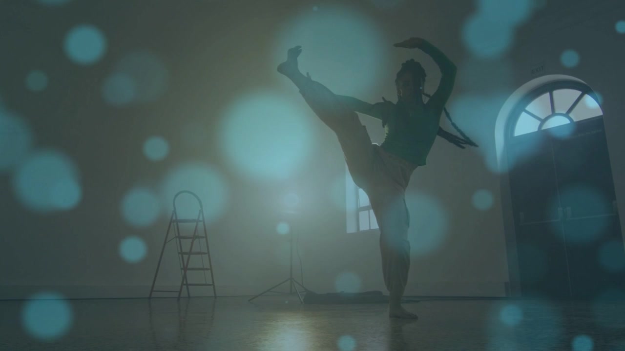 Woman dancer starting jump, rehearsing, spinning, kicking, backlit silhouette with bluish bokeh