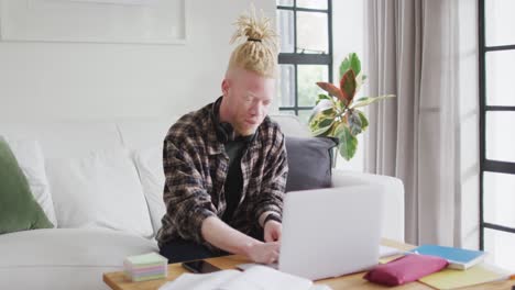 albino african american man with dreadlocks working and using laptop