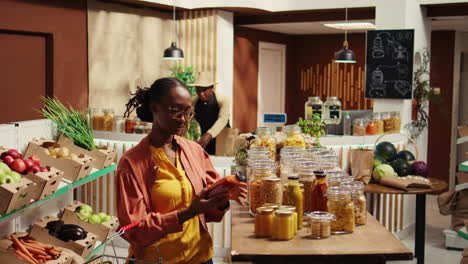 african american buyer putting pasta and organic sauce in a basket