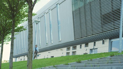 View-from-below-of-young-man-riding-a-bike-close-to-a-huge-building