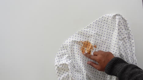 person pointing at a stain on a white shirt