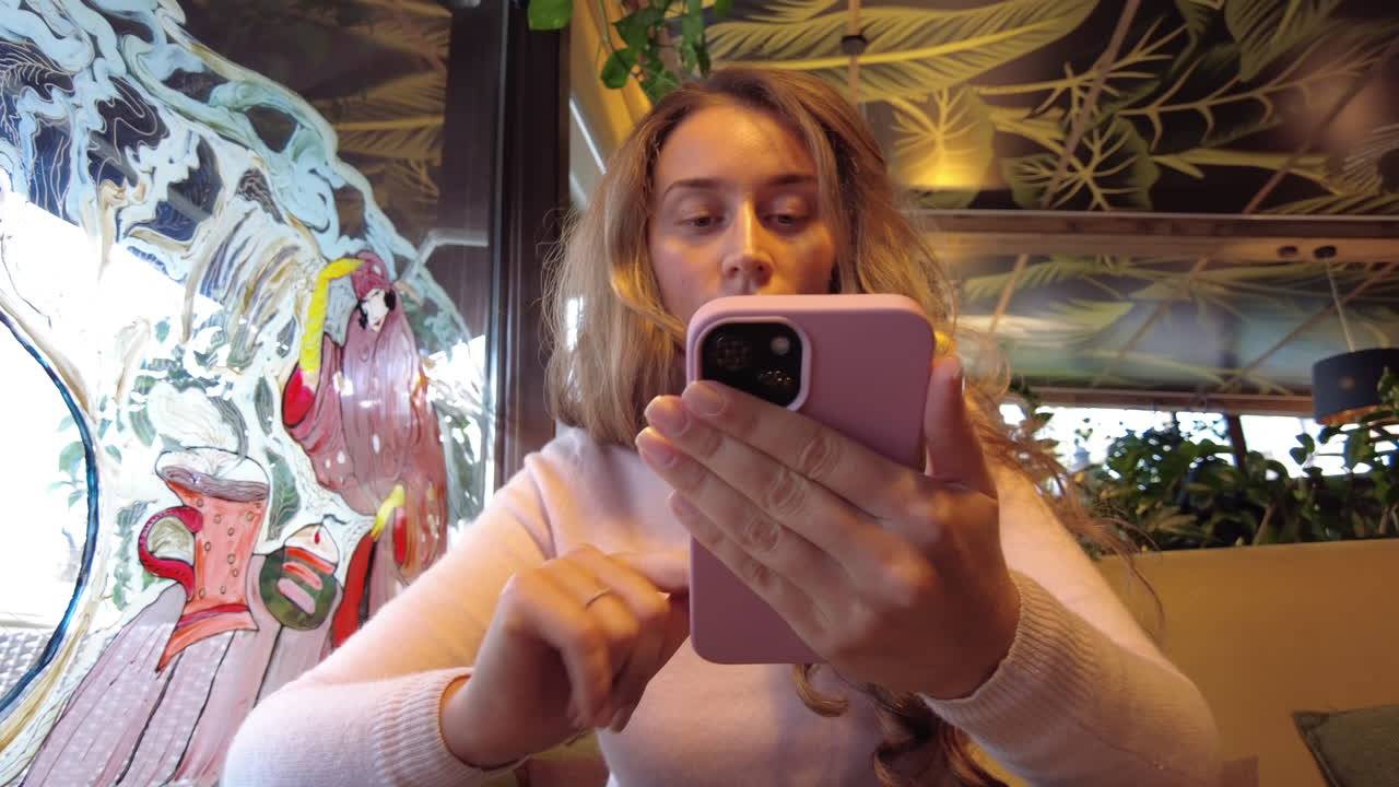 Blonde woman scrolling on her phone at a cafe