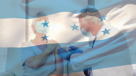 animation of flag of honduras waving over doctor wearing face mask and vaccinating senior woman