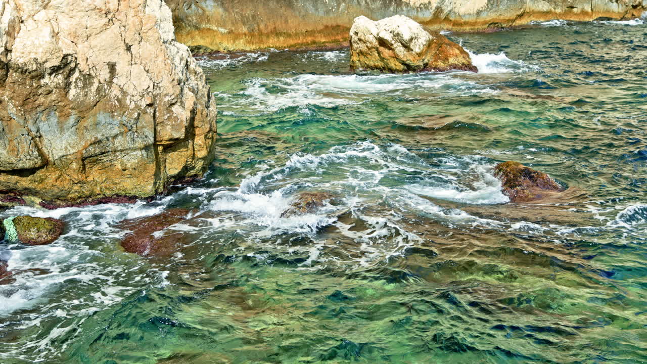 Onde turchesi dell'oceano che si infrangono contro le rocce costiere.