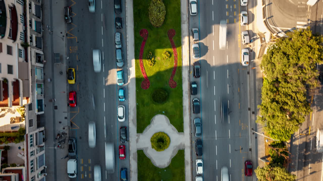 Top-down hyperlapse of cars moving fast on busy Italian, Genoa city roads with green divider and zebra crossings