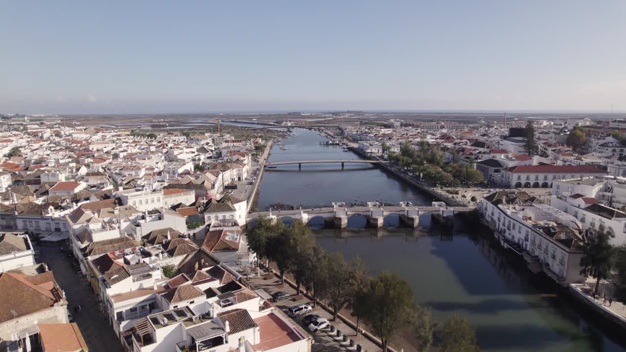 Vista orbital del Puente Antiguo sobre el río Gilão desde Tavira, casas blancas ribereñas en el centro.