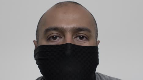 adult uk asian male putting on balaclava face mask indoors