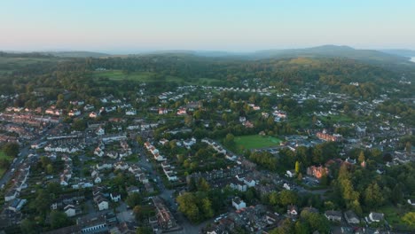 rural urban town amongst woodland and hills at sunrise. lateral camera movement. summer. windermere, cumbria, uk