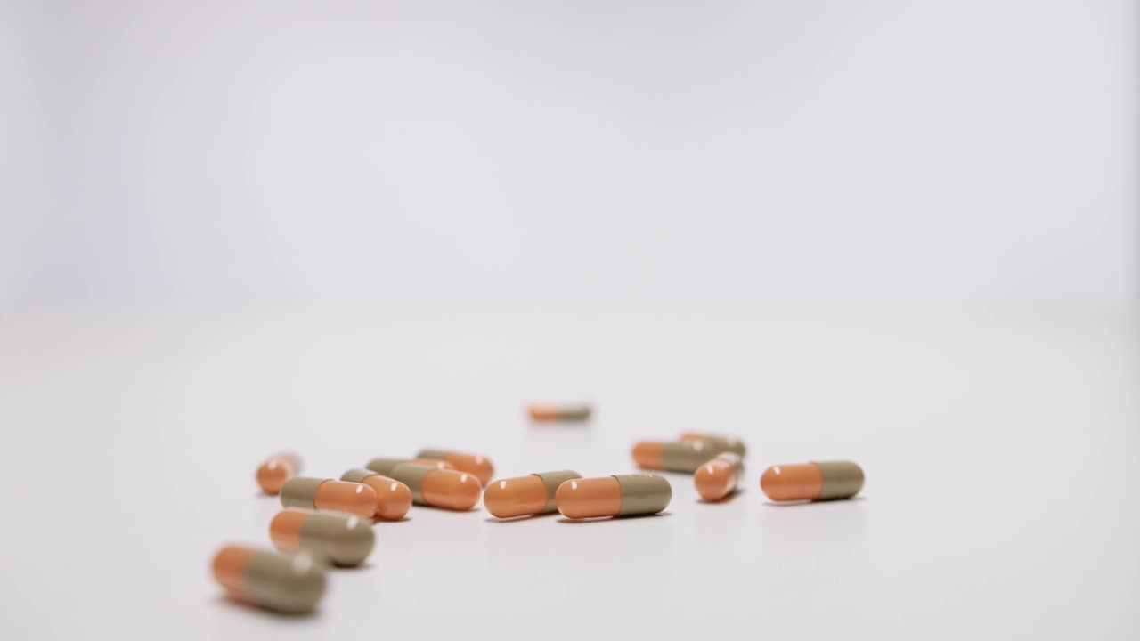 cápsulas médicas cayendo sobre fondo blanco en cámara lenta