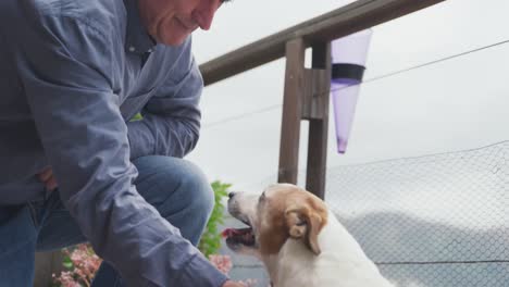 un hombre mayor y su perro en la terraza de su casa