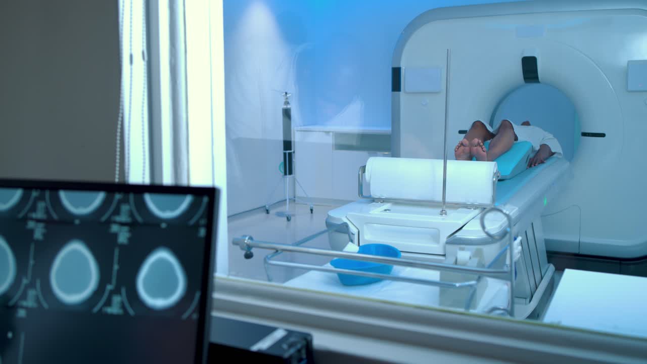Lo scanner si sta modificando, il tecnico sta toccando il monitor mentre rivede le sezioni, mentre il paziente rimane nel foro