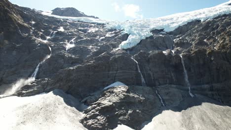 spectacular aerial view of glacier melting down, creating waterfalls on rocky wall