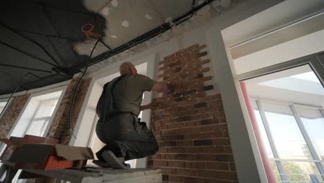 specialist installing decorative brick tiles on the wall. renovation in the loft style. construction works