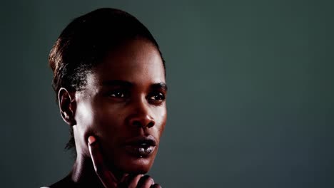 androgynous man posing against dark background