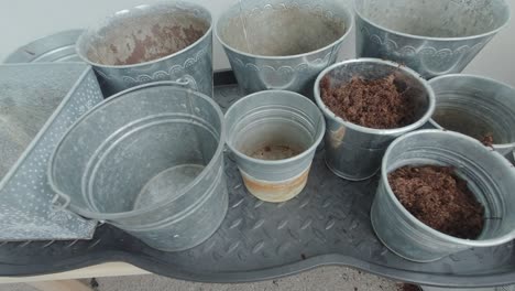 a hand belonging to a man is depositing soil into the buckets, gradually filling them with the loose earth