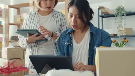 young asia businesswomen meeting check product purchase order on stock and save to tablet computer work at home office.