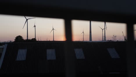 cinematic slow motion shot behind a railing, view of the sunset with wind turbines in the background
