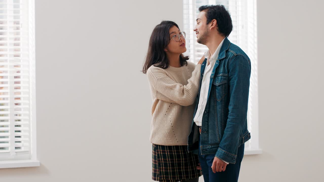 젊은 부부는 빈 아파트에 서서 서로 포옹하고, 이동을 즐기고, 웃고, 사랑에 빠지고, 행복하고, 이야기합니다.