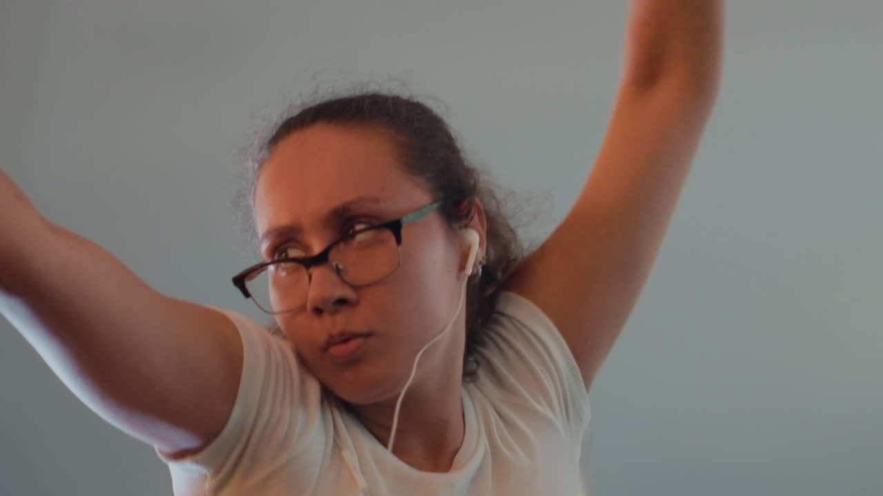 Woman stretching and singing under open sky with ponytail and glasses, vocal warmup and exuberant movements, arms raised and head tilted back, expressive face alternating between breathy chorus