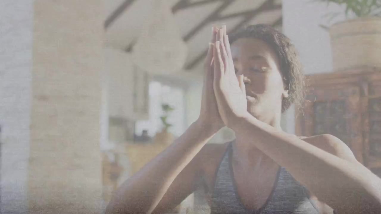 Mujer inhalando, uniendo las palmas en posición de oración en una habitación soleada, con una línea de respiración que traza sus manos para el bienestar.
