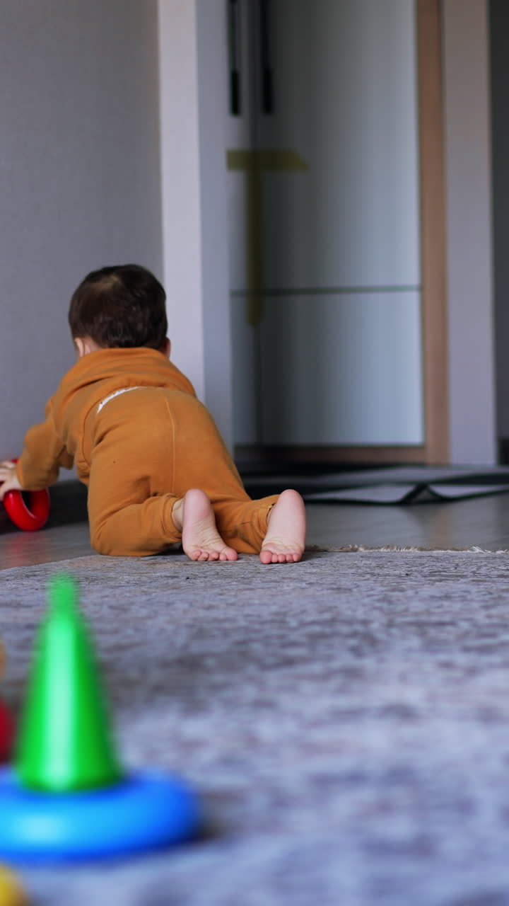 Small toddler quickly crawling by the room to reach the toy. Happy child takes the red ring and brings it to his mom. Vertical video