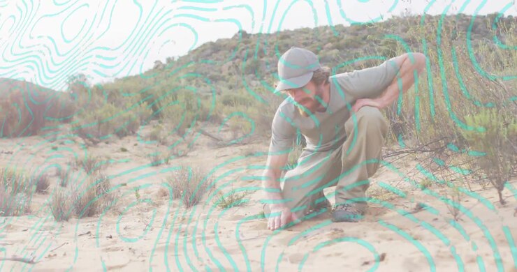 Spotting small pebbles, adult man kneeling and sifting sand, turquoise overlay highlighting geology