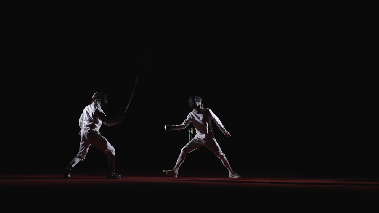 Two fencers compete in a fencing match
